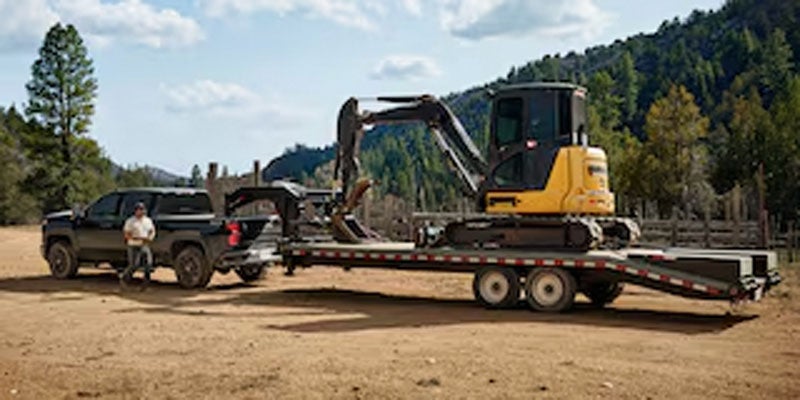 2026 Chevrolet Silverado 2500 HD towing a trailer with a backhoe in Orangeburg, SC, showcasing its impressive towing capability of up to 22,070 lbs. with advanced trailering systems for smooth and controlled hauling.